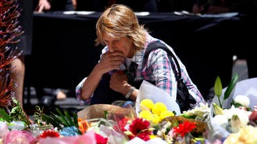 A woman reacts after placing a floral tribute amongst thousands of others that have been placed near the cafe where hostages were held for over 16-hours, in central Sydney December 16, 2014. reuters