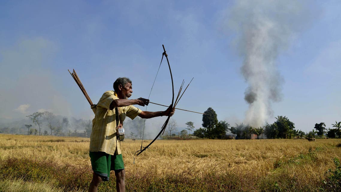 ndian tribal villager or Adivasi stands with a bow and arrow as homes burn in the village of Tenganala in Sonitpur District, some 250kms east of Guwahati on December 24, 2014. (afp) india bow arrow