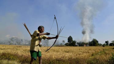 ndian tribal villager or Adivasi stands with a bow and arrow as homes burn in the village of Tenganala in Sonitpur District, some 250kms east of Guwahati on December 24, 2014. (afp) india bow arrow 
