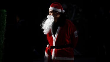 A salesman dressed as Santa Claus waits for customers at the entrance of a shop in Beijing on December 25, 2014. AFP