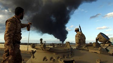 Members of the Libyan army stand on a tank as heavy black smoke rises from the Benghazi's port in the background on Dec. 23, 2014. (AFP)