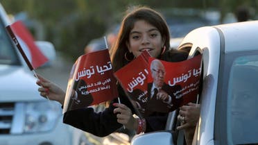 A young girl holds flags from a car as supporters of Tunisian newly-elected President Beji Caid Essebsi celebrate his victory on December 22, 2014 in Tunis. AFP