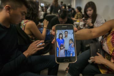  A relative shows a picture of alleged passengers who were travelling on missing Malaysian air carrier AirAsia flight QZ8501. (AFP)