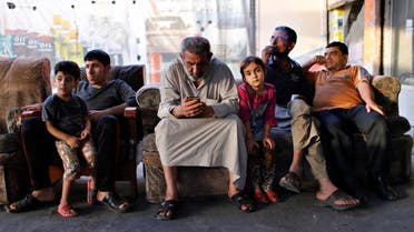 An Iraqi Shi'ite man (C) uses his phone as he sits at an outdoor cafe in Sadr City in Baghdad. (File photo: Reuters) iraqi family iraq father kids