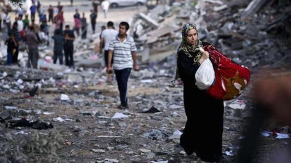 A Palestinian woman takes some of her belongings from her destroyed home in Gaza City was targeted by Israeli airstrikes. (AFP)