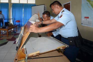 Indonesian military officers examine a piece of wreckage from AirAsia flight QZ8501, lost over the Java Sea, at the military base in Pangkalan Bun, the town with the nearest airstrip to the crash site, in Central Kalimantan on January 2, 2015. (AFP)