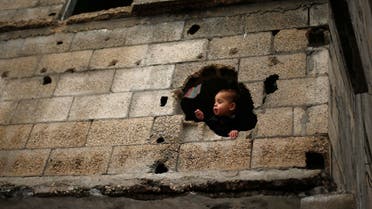 A Palestinian boy looks out through a hole in his family house witnesses said was damaged by Israeli shelling during the July-August Gaza war, Gaza City January 4, 2015. (Reuters)