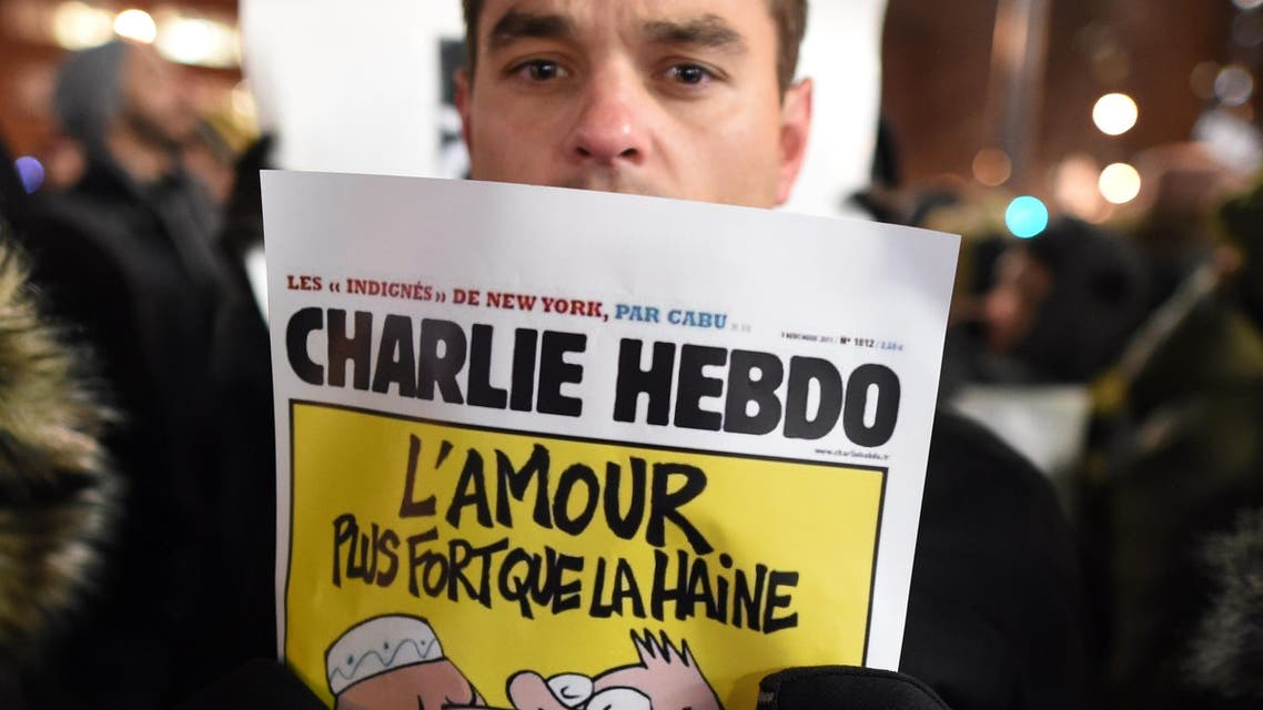 A man holds a cartoon as people gather on Union Square January 7, 2015 in New York in memory of the victims of the attack on the offices of the satirical weekly Charlie Hebdo in Paris. (AFP)