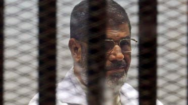 Former Egyptian President Mohamed Mursi sits behind bars with other Muslim Brotherhood members at a court in the outskirts of Cairo, December 29, 2014. (Reuters)