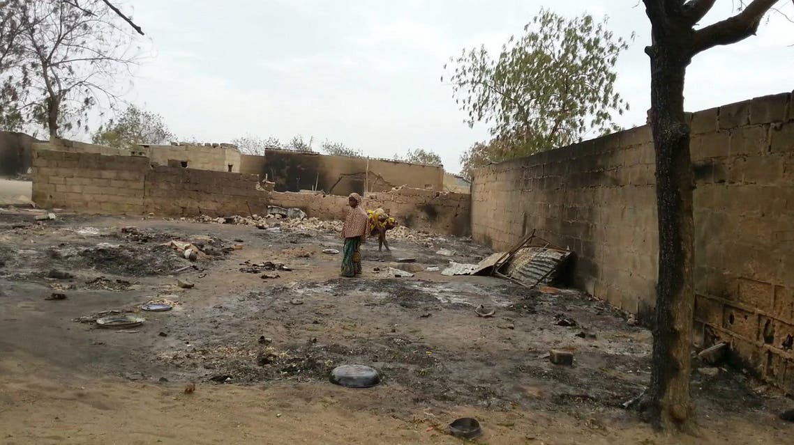 In this image shot with a mobile phone, a young girl stands amid the burned ruins of Baga, Nigeria, on Sunday, April 21, 2013. AP