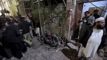 A Pakistani police officer and local residents gather next to a damage motorcycle at the site of a suicide bombing in Rawalpindi, Pakistan, Friday, Jan. 9, 2015. AP