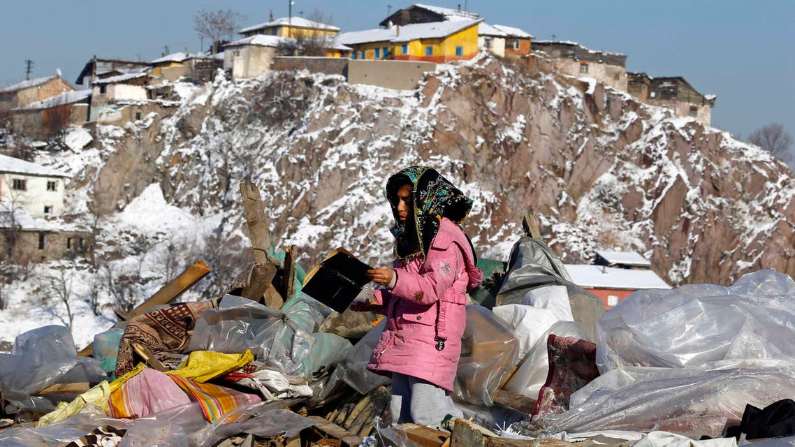 A Syrian refugee girl looks at a book she picked up from the debris of dismantled makeshift shelters of Syrian refugees, in the Hacibayram district of Ankara January 9, 2015. (Reuters)