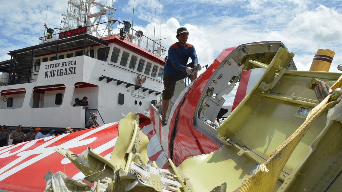 An Indonesian worker (top C) cuts the tail of the AirAsia flight QZ8501 in Kumai on January 12, 2015, after debris from the crash was retrieved from the Java sea. AFP
