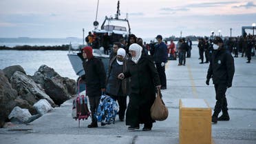 In this Nov. 27, 2014 file photo, women walk with their belongings just after disembarking from a crippled freighter carrying hundreds of refugees trying to migrate to Europe. File Photo AP