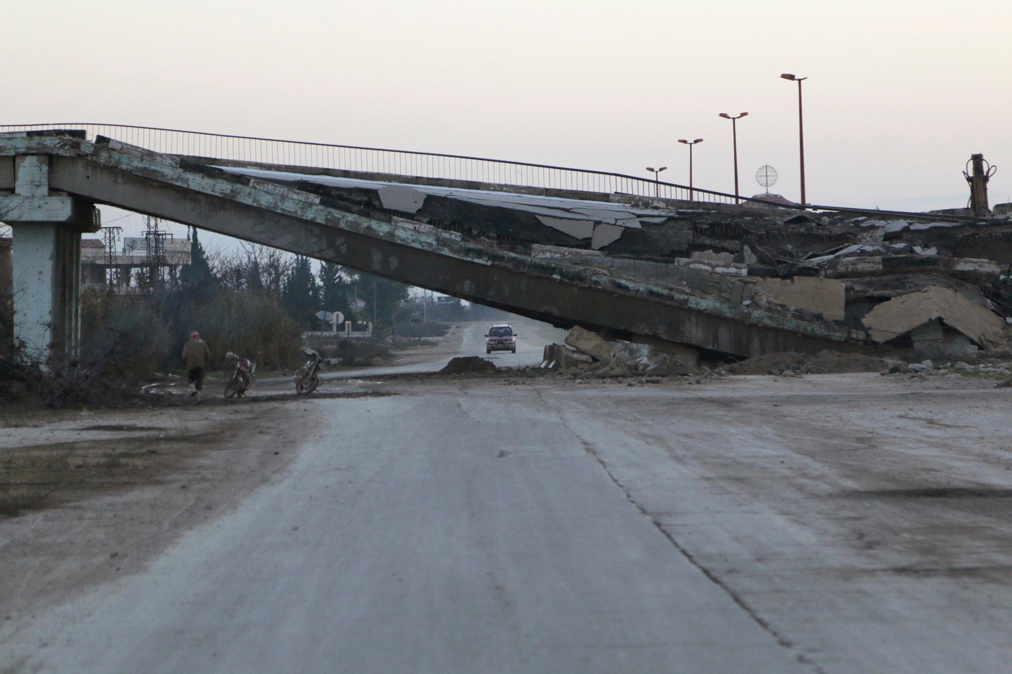 Residents drive by a damaged bridge on a highway that connects Aleppo with Damascus in Maaret al-Naaman town in Idlib province Jan. 14, 2015. (Reuters)