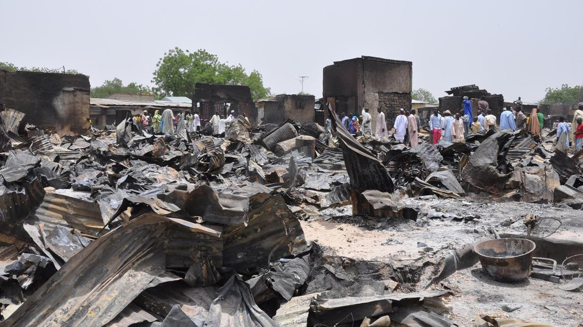 people stand outside burnt houses following an attack by Islamic militants in Gambaru, Nigeria. File AP