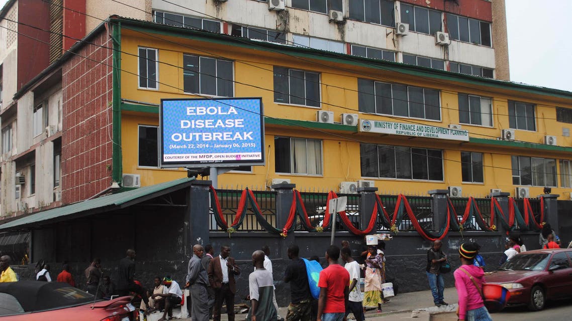 Pedestrians walk past a sign reading Ebola disease outbreak outside the Ministry of Finance in Monrovia January 12, 2015. (Reuters)