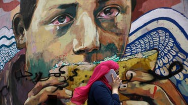 A woman talks on her tablet phone while walking past graffiti in Mohammed Mahmoud Street near Tahrir Square, in downtown Cairo, Egypt, Wednesday, Sept. 17, 2014. AP