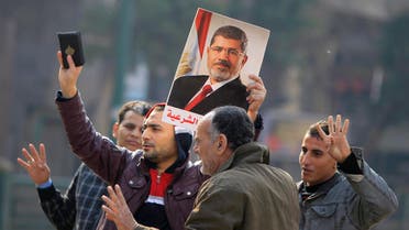 Supporters of the Muslim Brotherhood and ousted Egyptian President Mohamed Mursi hold a copy of the Koran and Mursi's picture at Talaat Harb Square, in Cairo, Jan. 25, 2015. (Reuters)