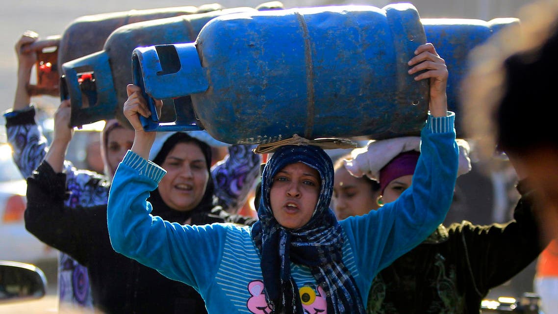 Women carry gas cylinders to fill them at a distribution point in Cairo Jan. 19, 2015. (Reuters)