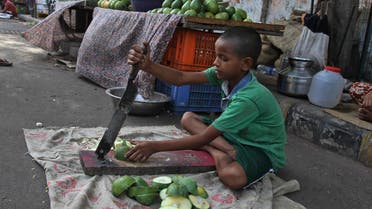 An Indian boy cuts mangoes for sale by a road side as he helps his family in the evening in Ahmadabad, India, Wednesday, June 11, 2014. India recently passed a law aimed at fighting child labor by making education compulsory up to age 14. But grinding poverty still leads many kids to work. Thursday, June 12 marks the World Day against Child Labor. (AP Photo/Ajit Solanki)