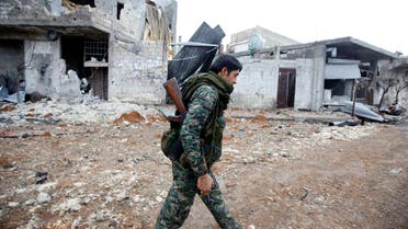A fighter of the Kurdish People's Protection Units (YPG) walks past damaged buildings in the northern Syrian town of Kobani Jan. 30, 2015.  (Reuters)
