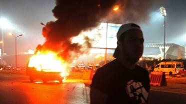 A soccer fan is seen near a police car, which was set on fire by fireworks, during clashes between soccer fans and security forces in front of a stadium on the outskirts of Cairo February 8, 2015. (Reuters)