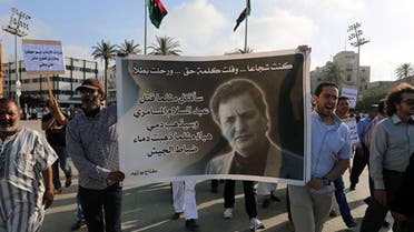 Protesters hold a banner bearing the portrait of Miftah Bouzeid, editor of the weekly newspaper Burniq, during a rally in Tripoli’s Martyrs' Square  AFP 