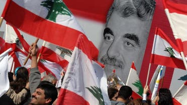 Lebanese government supporters hold Lebanese flags as they attend a rally to commemorate the death of former Prime Minister Rafik Hariri (pictured in the background) in downtown Beirut, Lebanon Wednesday, Feb. 14, 2007. AP