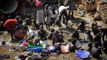 In this Friday Dec. 27 , 2013 file photo, displaced people bathe and wash clothes in a stream inside a United Nations compound which has become home to thousands of people displaced by the recent fighting, in Juba, South Sudan. AP