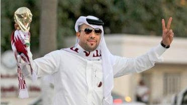A Qatari fan holds a replica of the World Cup trophy as he celebrates in Doha