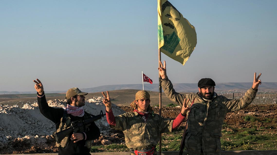 Syrian Kurdish militia members of YPG make V-sign next to poster of Abdullah Ocalan, jailed Kurdish rebel leader, and a Turkish army tank in the background in Esme village in Aleppo province, Syria, Sunday, Feb. 22, 2015. (AP)