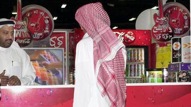 Saudi man walks in front of Coke stand AP