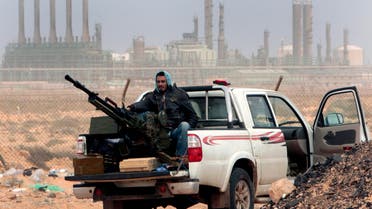 an anti-government rebel sits with an anti-aircraft weapon in front an oil refinery, after the capture of the oil town of Ras Lanouf, eastern Libya. (AP)