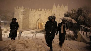Ultra-Orthodox Jewish men walk near Damascus Gate in Jerusalem’s Old City as snow falls on February 19, 2015. (AFP)