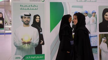 In this Tuesday, April 22, 2014 photo, Emirati women pass by posters at a government stand during the Careers UAE opening exhibition exclusively for UAE Nationals in Dubai, United Arab Emirates. (AP)