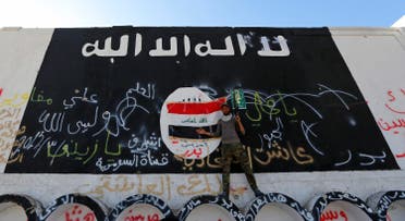 A member of militias known as Hashid Shaabi stands next to a wall painted with the black flag commonly used by Islamic State militants, in the town of al-Alam March 10, 2015. (Reuters)