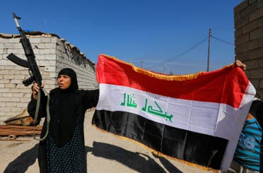A woman with a weapon and the Iraqi flag welcomes her relative who is part of militias known as Hashid Shaabi, in the town of al-Alam March 10, 2015. (Reuters)
