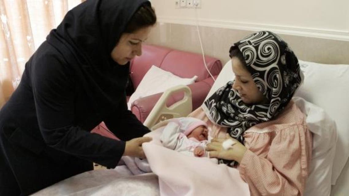 An Iranian nurse gives one-day-old baby girl to her mother at a hospital in Tehran AP