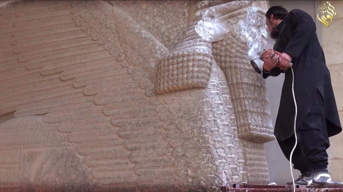 A still from a video showing an ISIS militant using a power tool to deface an Assyrian monument in the ancient city of Hatra, northern Iraq. (Photo courtesy of Twitter)