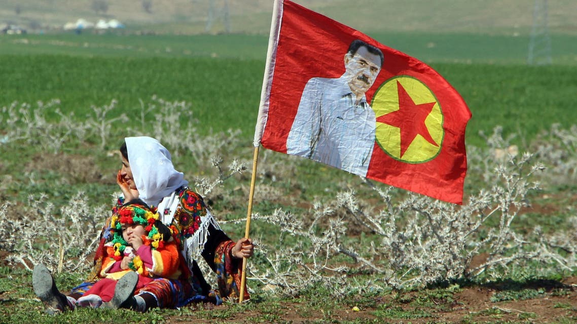 A Turkish Kurdish woman with a child sits next to a PKK flag with a picture of the imprisoned Kurdish rebel leader Abdullah Ocalan during a women's day event in Silopi, in Kurdish dominated southeastern Turkey, March 2, 2015. REUTERS