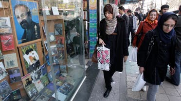 Iranian pedestrians walk past a book shop decorated with a poster of Asghar Farhadi, Iranian Oscar winner filmmaker, in central Tehran, Iran, Tuesday, Feb. 28, 2012. AP