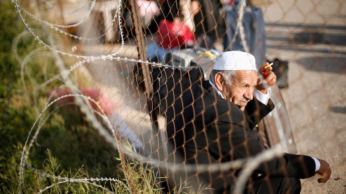 A Palestinian man sits by a fence as he waits for a travel permit to cross into Egypt, at the Rafah crossing between Egypt and the southern Gaza Strip March 9, 2015. (Reuters)