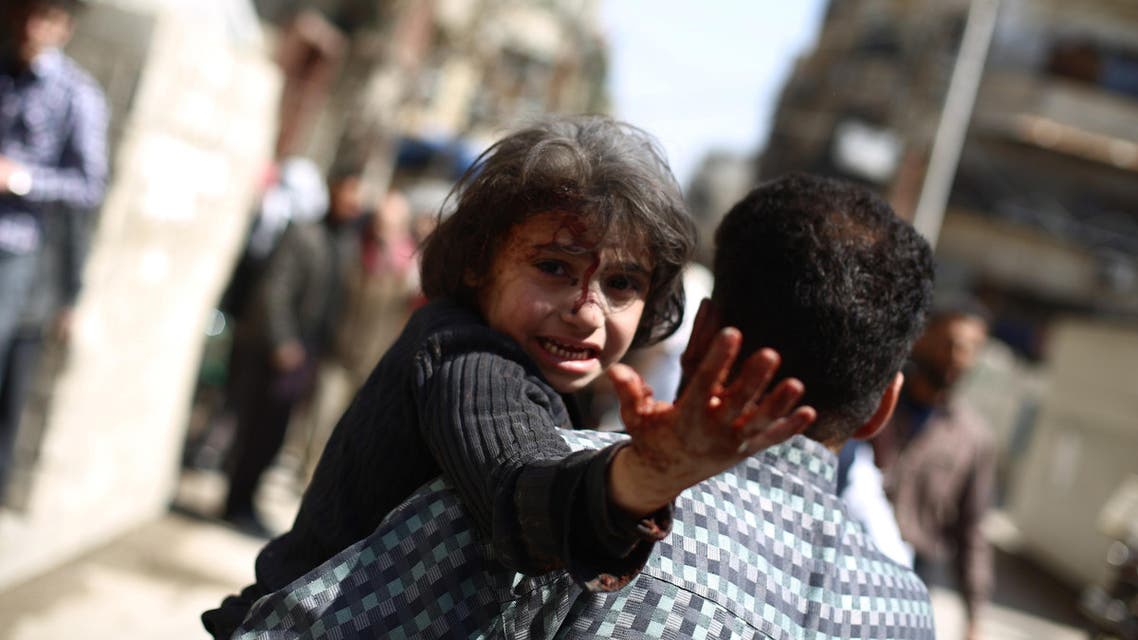 A man carries a wounded child in the rebel-held area of Douma, east of the capital Damascus, following reported air strikes by regime forces on March 15, 2015. AFP
