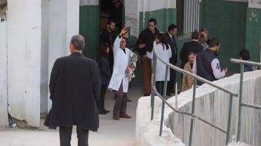 A Tunisian doctor gestures as he holds flowers amongst embassy staff of different countries at the morgue of the Charles Nicolle hospital in Tunis Tunisia, Thursday, March 19, 2015. (AP)