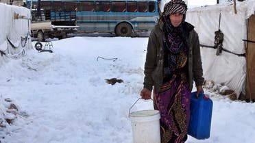 A Syrian woman carries water as she walks through snow at a refugee camp in al-Majdal village, Bekaa valley, east Lebanon, Thursday, Jan. 8, 2015. (AP)