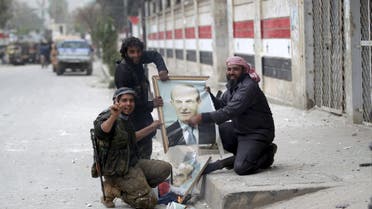 Rebel fighters gesture as they damage a picture of late Syrian president Hafez al-Assad, father of Syrian President Bashar al-Assad, in Idlib city, after they took control of the area March 28, 2015. (Reuters)