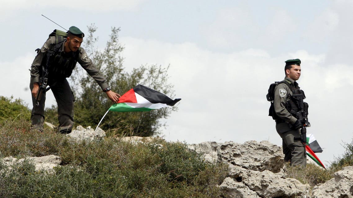 Israeli border policeman remove Palestinian flags during a demonstration by Palestinians marking Land Day and against Jewish settlements in Wadi Foukeen near the West Bank city of Bethlehem March 30, 2015. (Reuters)