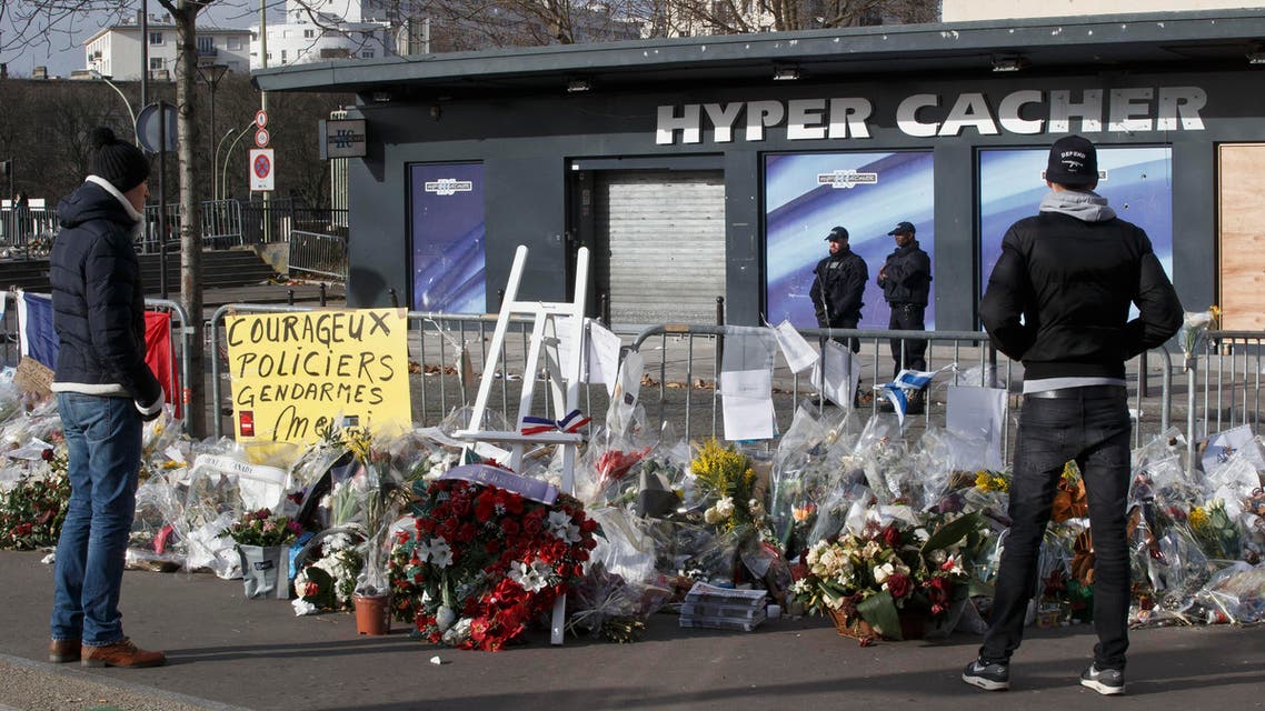 People look at flowers laid outside the kosher grocery store in Paris, Sunday Feb. 8, 2015, where four people where killed in a terror attack. (AP)