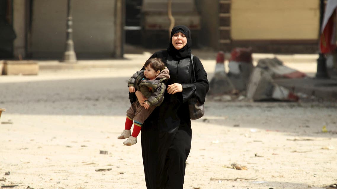 A woman carrying a child reacts at a damaged site after what activists said was shelling by forces loyal to Syria's president Bashar al-Assad on a mosque in Idlib city, after rebels took control of the area April 3, 2015. Reuters